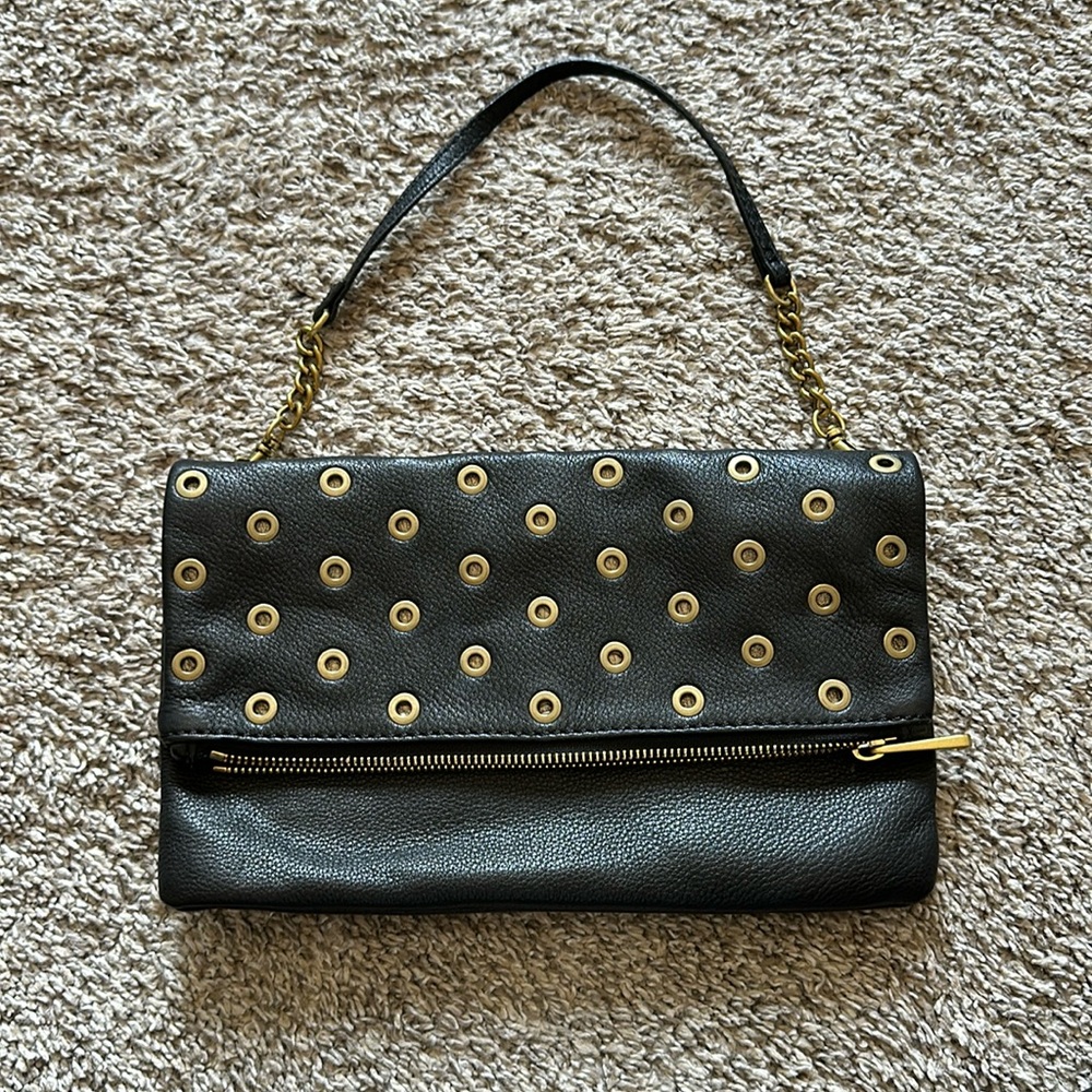 Fossil leather clutch with brass rivets and detachable strap.